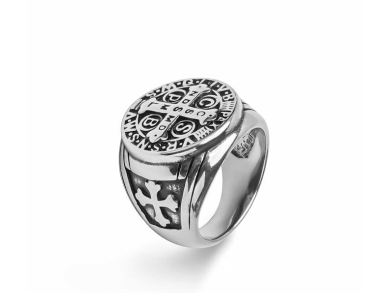 May include: A silver ring with a detailed design featuring a cross and the words "S.P.Q.R.  INRI  V.R.S.  N.S.  I.H.S.  M.S.S.  D.O.M.  P.P.  C.S.  P.X.  A.V.S.  P.R.A.Y.  F.E.A.R.  N.O.T.  S.O.N.  O.F.  G.O.D.  L.W.S.  B.M.S.  D.C.S.  C.P.S.  S.C.S.  S.P.Q.R."