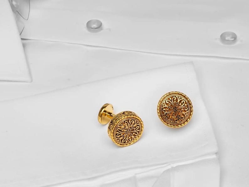 May include: A pair of gold cufflinks with an intricate floral design.