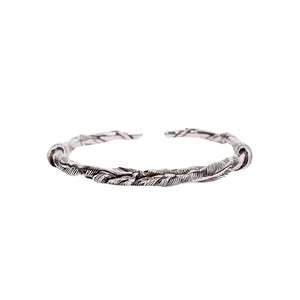 Puede incluir: Un brazalete plateado con un diseño texturizado y orgánico. El brazalete parece estar hecho de hebras entrelazadas, posiblemente parecidas a vides o ramas. El diseño abierto permite ponérselo y quitárselo fácilmente. El brazalete es una joya.