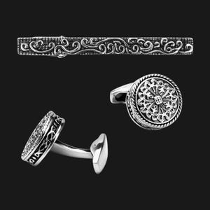 K&ouml;nnte beinhalten: Ein Set silberner Manschettenkn&ouml;pfe und ein Krawattenclip mit filigranen Blumenmustern.