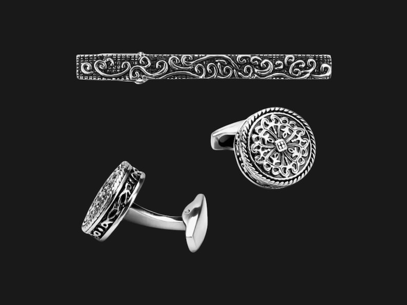 K&ouml;nnte beinhalten: Ein Set silberner Manschettenkn&ouml;pfe und ein Krawattenclip mit filigranen Blumenmustern.
