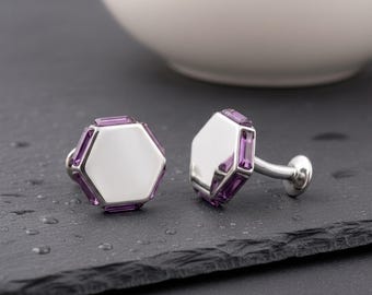 May include: A pair of hexagonal cufflinks featuring a polished silver-tone center and a border of small, rectangular purple gemstones. The cufflinks have a metallic silver-tone post and a rounded backing, showcasing a clean and geometric design.