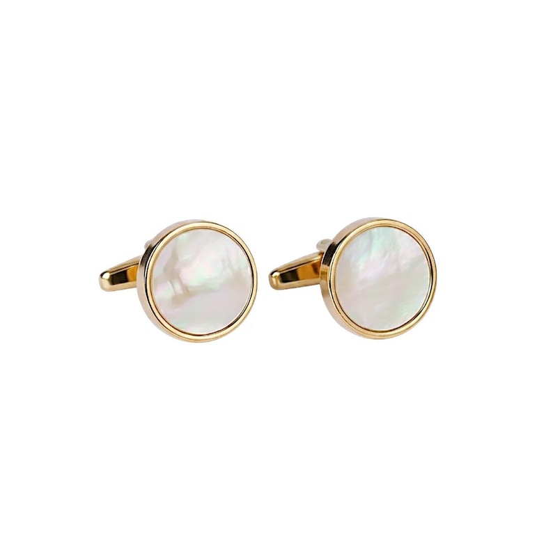 May include: A pair of gold-toned cufflinks with a round, iridescent mother-of-pearl center. The cufflinks have a classic design, suitable for formal wear or adding a touch of elegance to any outfit.