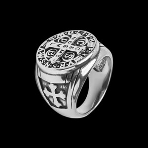 May include: A silver ring with a detailed design featuring a cross and the words "S.P.Q.R." and "INRI".