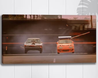 May include: A white Dodge Charger and an orange Toyota Supra race down a street. The Charger is in the foreground, while the Supra is in the air, having just jumped over a wooden plank. The background is blurred, suggesting speed.