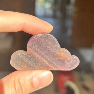 May include: A small, pink and purple cloud-shaped crystal with swirls of color.