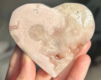 May include: A heart-shaped pink and white crystal with a rough, natural texture.
