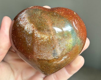 May include: A heart-shaped polished stone with brown, green, and white swirling patterns.