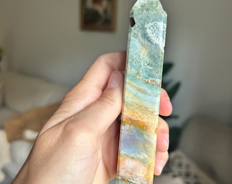 May include: A green, yellow, and white banded crystal point with a pointed tip. The crystal is smooth and polished.