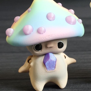 May include: A small, beige figurine with a rainbow mushroom hat. The mushroom has pink polka dots and a light blue, pink, and yellow gradient. The figurine has a purple gem on its chest.