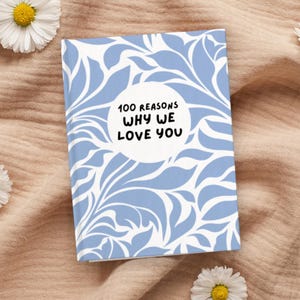 May include: A blue and white journal with a floral pattern and the text "100 Reasons Why We Love You" in a circle.