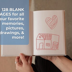 May include: A white blank notebook with 128 pages, open to reveal a red hand-drawn heart and house. The text "128 BLANK PAGES for all your favorite memories, pictures, drawings, & more!" is visible on the left page.