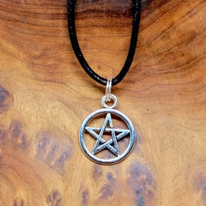 May include: A silver pentacle pendant on a black leather cord necklace.