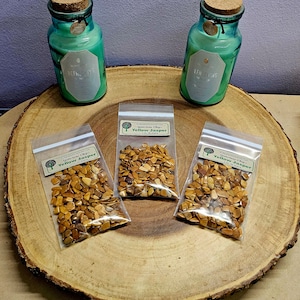 May include: Three small bags of yellow jasper chips, each labeled "Gemstone Chips Yellow Jasper", are arranged on a wooden slice. Two teal glass bottles with cork tops are on the wooden slice. One bottle is labeled "Refreshing" and the other is labeled "Luminous".