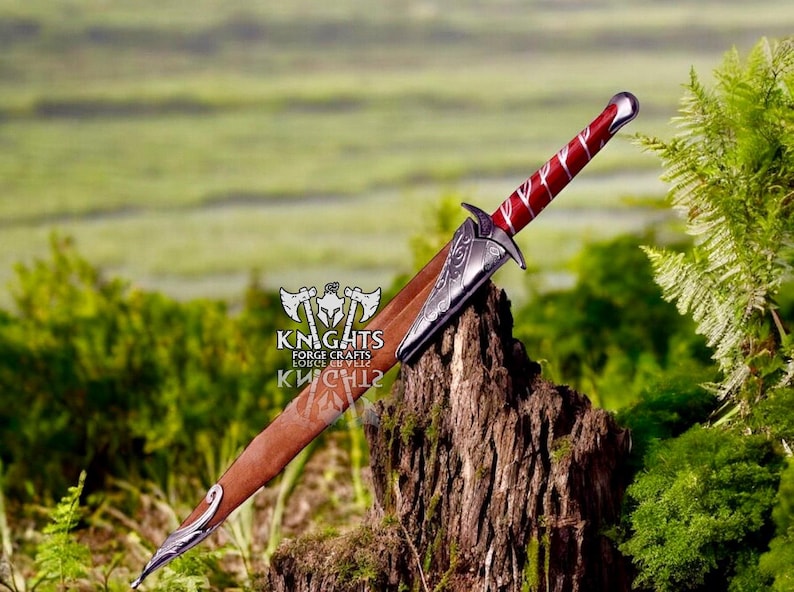May include: A decorative dagger with a red and silver handle and a brown sheath. The blade is partially visible, and the dagger rests on a tree stump. The handle has a red and white pattern. The dagger is a medieval-themed item.