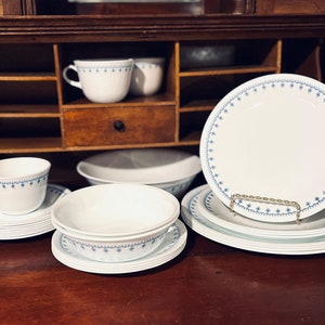 May include: A set of white Corelle dinnerware with a blue snowflake pattern. The set includes plates, bowls, and cups.
