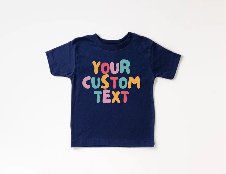 May include: A navy blue t-shirt with the text "YOUR CUSTOM TEXT" in colorful, bubble-like letters.