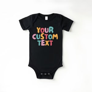 May include: Black baby onesie with short sleeves and a colorful text graphic that says "YOUR CUSTOM TEXT".