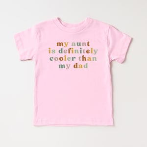 May include: Pink toddler t-shirt with the text "my aunt is definitely cooler than my dad" in colorful letters.