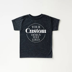 Op de afbeelding: Een donkergrijs T-shirt met een witte cirkel op de voorkant met de tekst "YOUR Custom DESIGN TEXT LOGO".
