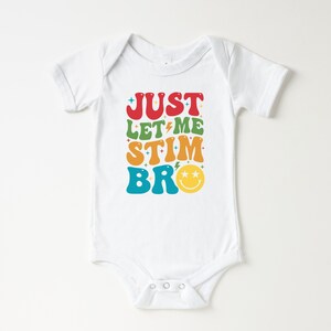 K&ouml;nnte beinhalten: Wei&szlig;er Baby Strampler mit dem Text "JUST LET ME STIM BRO" in Regenbogenfarben mit einem Smiley.