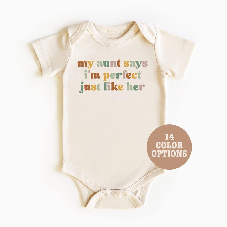 May include: A cream-colored baby onesie with the text "my aunt says i'm perfect just like her" in colorful letters. The text is in a retro font style. There are 14 color options available.
