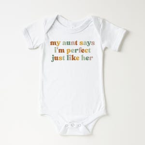 May include: White baby onesie with the text "my aunt says i'm perfect just like her" in colorful retro font.
