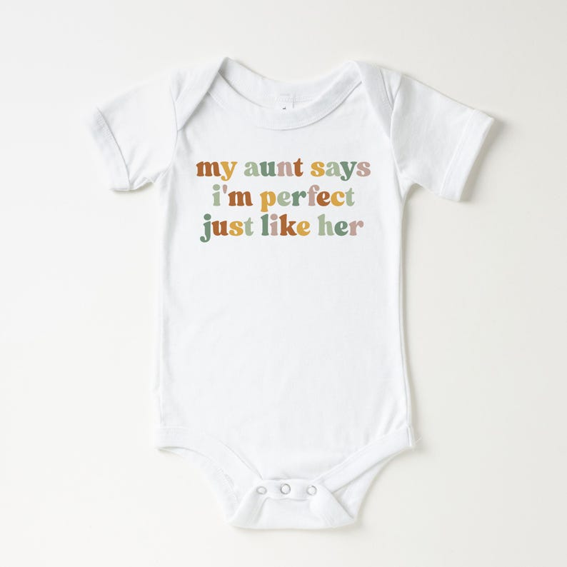 May include: White baby onesie with the text "my aunt says i'm perfect just like her" in colorful retro font.