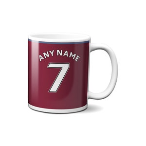 May include: White ceramic mug with a burgundy design. The mug has a blue stripe around the top and the text "ANY NAME 7" printed on the front.