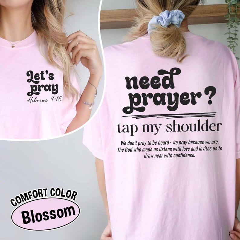K&ouml;nnte beinhalten: Hellrosa T-Shirt mit den Aufdrucken "Let's pray" und "Hebrews 4:16" auf der Vorderseite. Auf der R&uuml;ckseite des Shirts steht "need prayer? tap my shoulder" mit einer Botschaft. Das Shirt ist Comfort Color Blossom.
