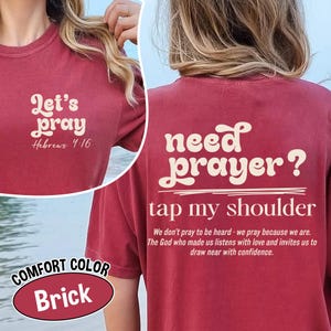 K&ouml;nnte beinhalten: Ziegelrotes T-Shirt mit dem Text "Let's pray" und "Hebrews 4:16" auf der Vorderseite. Auf der R&uuml;ckseite des Shirts steht "need prayer? tap my shoulder" mit einem Zitat darunter. Das Shirt ist mit "Comfort Color" gekennzeichnet.