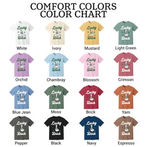 Puede incluir: Una carta de colores de camisetas Comfort Colors. Cada camiseta presenta un gr&aacute;fico de un pato con el texto "Lucky Duch". Los colores incluyen blanco, marfil, mostaza, verde claro, orqu&iacute;dea, chambray, flor, carmes&iacute;, azul vaquero, musgo, ladrillo, &ntilde;ame, pimienta, negro, azul marino y espresso.