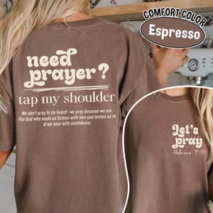 K&ouml;nnte beinhalten: Espressofarbenes T-Shirt mit dem wei&szlig;en Text "need prayer? tap my shoulder". Das Shirt hat auch den Text "We don't pray to be heard - we pray because we are..." und "Let's pray Hebrews 4:16".