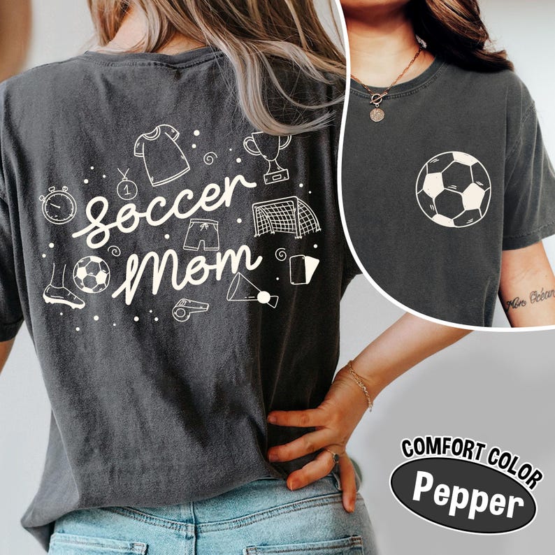 K&ouml;nnte beinhalten: Dunkelgraues Comfort Color T-Shirt mit einem wei&szlig;en Fu&szlig;ball-Grafik auf der Vorderseite und einem "Soccer Mom"-Design auf der R&uuml;ckseite. Das R&uuml;ckendesign enth&auml;lt fu&szlig;ballbezogene Illustrationen. Das Shirt besteht aus einem weichen, bequemen Material.
