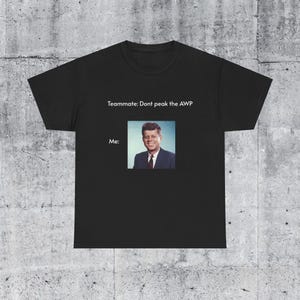 May include: Black t-shirt with the text "Teammate: Dont peak the AWP" and a photo of John F. Kennedy below it. The text "Me:" is above the photo.