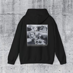 May include: Black hooded sweatshirt with a graphic print of four black and white photos of a city scene. The text "شرفة مشرفة" is printed in white below the photos.