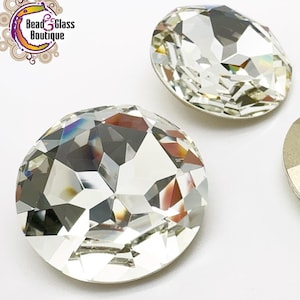 May include: Three round glass rhinestones, two clear and one gold. The clear rhinestones have a faceted design. The gold rhinestone has a flat, matte finish.