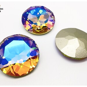 May include: Three iridescent, faceted crystal rhinestones. The crystals have a round shape with a flat back and a multi-colored, shimmering effect, reflecting hues of blue, yellow, and orange. The image includes the text "Bead & Glass Boutique".