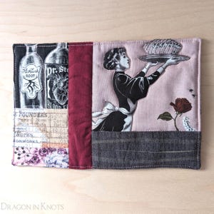 Puede incluir: Un artículo de tela con un diseño de collage. Presenta ilustraciones de estilo vintage de botellas de boticario, una mujer sosteniendo una bandeja y elementos florales y textuales. La paleta de colores incluye negro, blanco, burdeos, rosa y gris.