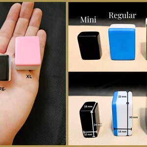 Op de afbeelding: Drie verschillende maten mahjong-tegels: mini, standaard en extra groot. De mini-tegel is roze, de standaardtegel is zwart en de extra grote tegel is roze. De tegels worden op een hand getoond, met afmetingen in millimeters.