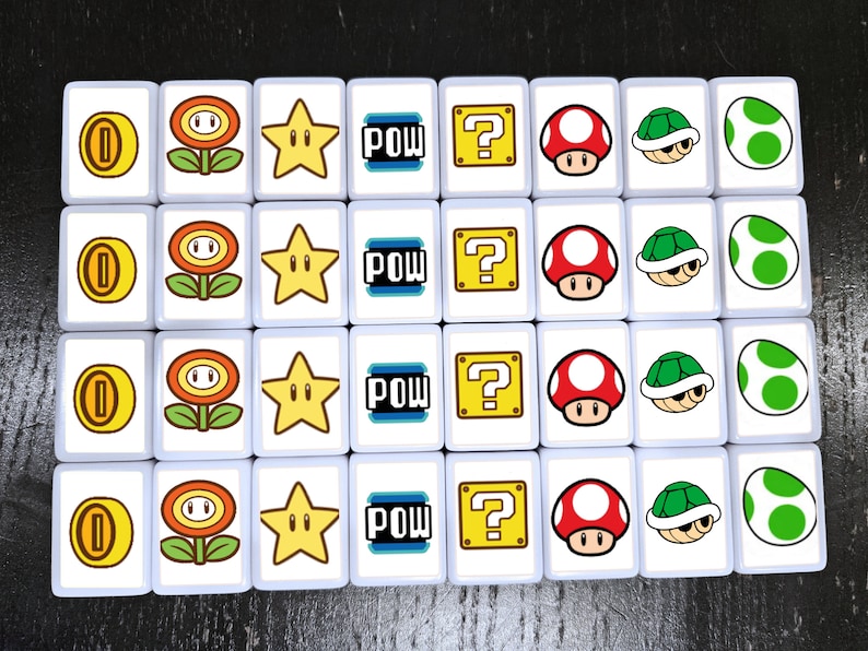 May include: A set of 16 white square tiles with different images from the Super Mario Bros. video game. The images include a 1-up mushroom, a flower, a star, the word "POW", a question mark block, a mushroom, a turtle shell, and an egg.