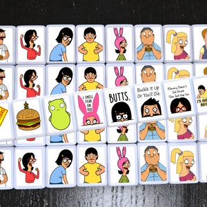 K&ouml;nnte beinhalten: Ein Satz von 25 quadratischen Kacheln mit Figuren aus der Zeichentrickserie Bob's Burgers. Jede Kachel zeigt eine andere Figur oder einen anderen Spruch aus der Serie, darunter "Bob's Burgers", "I Smell Fear On You", "Butts", "Buckle It Up Or You'll Die" und "Mommy Doesn't Get Drunk She Just Has Fun".