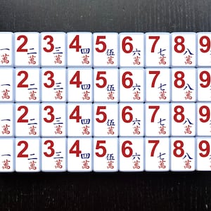May include: A set of 36 white tiles with red numbers and Chinese characters. The tiles are arranged in a 4x9 grid. The numbers on the tiles range from 1 to 9. The Chinese characters represent the numbers in Chinese.
