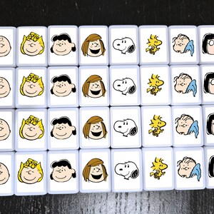 May include: A set of 20 white tiles with images of Peanuts characters. Each tile features a different character, including Charlie Brown, Snoopy, Lucy, and Linus. The tiles are arranged in a grid pattern.