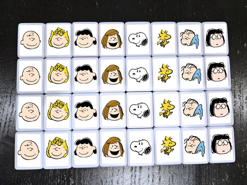 May include: A set of 20 white tiles with images of Peanuts characters. Each tile features a different character, including Charlie Brown, Snoopy, Lucy, and Linus. The tiles are arranged in a grid pattern.
