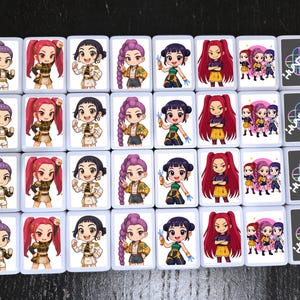 May include: A collection of rectangular cards featuring cartoon illustrations of anime-style characters with various hairstyles and outfits. Some cards display a group of characters, while others have the word "HUNTRA" with a colorful design.