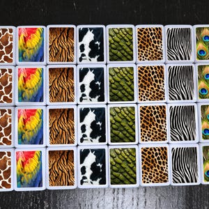 May include: Twenty-four white square tiles with different animal print designs. The designs include giraffe, peacock, zebra, tiger, cow, and snake patterns.