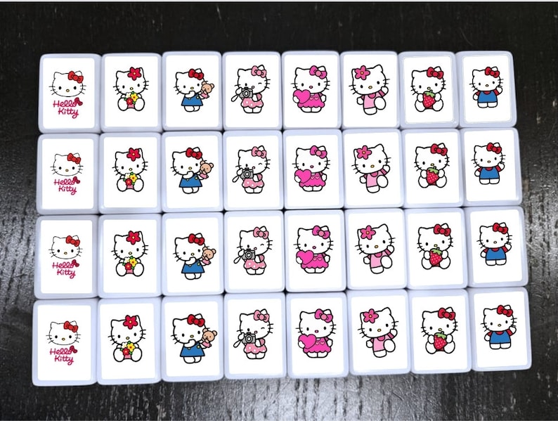 May include: A set of 16 white ceramic tiles with Hello Kitty images. Each tile features a different Hello Kitty design, including Hello Kitty holding a camera, a heart, a strawberry, and a teddy bear. The tiles are perfect for playing games or decorating a room.