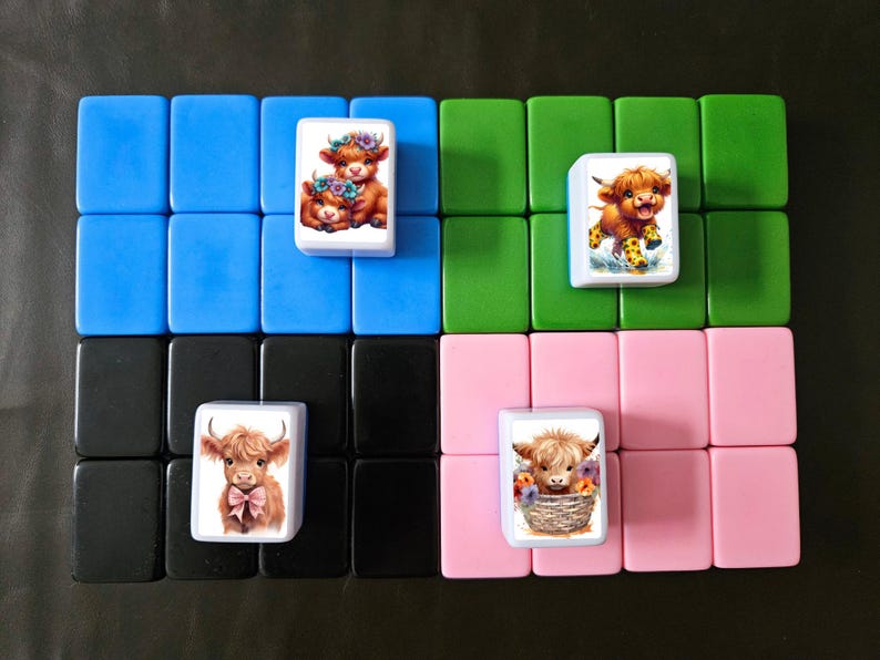 May include: Four white tiles with colorful images of Highland cows. The tiles are arranged in a 2x2 grid on a black, blue, green, and pink background.