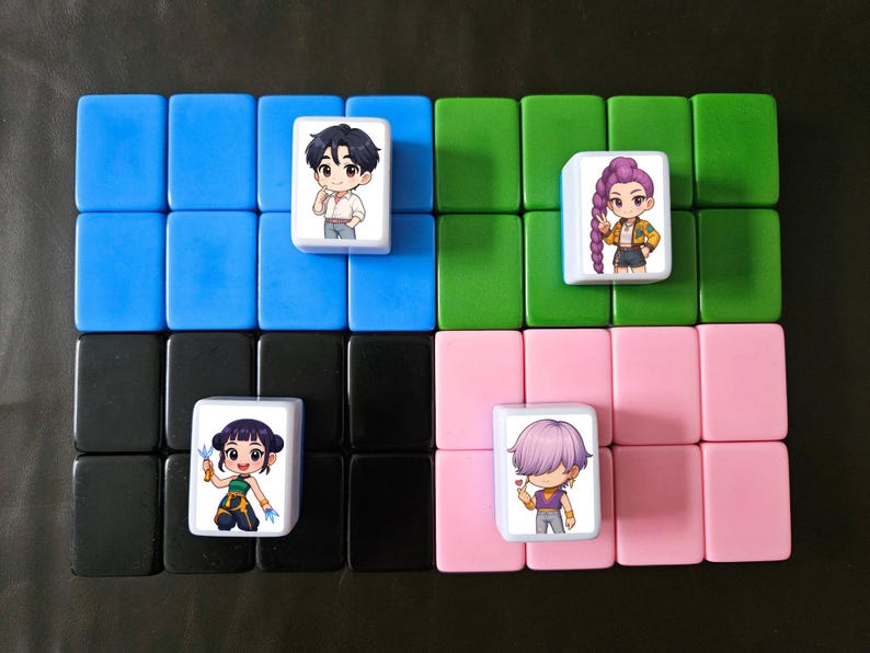 May include: A collection of colorful Mahjong tiles arranged in a grid. Four tiles feature anime-style character illustrations. The tiles are set against a background of blue, green, pink, and black tiles, creating a visually appealing pattern.